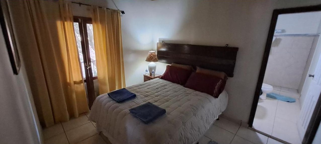 Double bedroom with yellow curtains and a view into its private bathroom