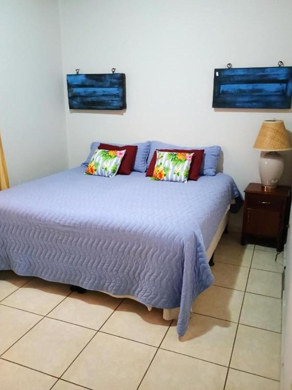 King bedroom with rustic wooden headboard and warm tile floors