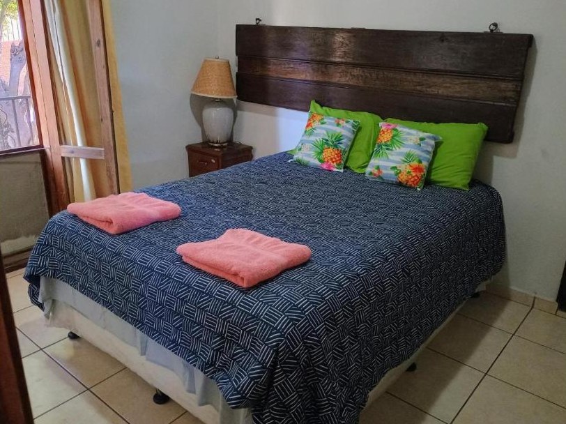 Queen bedroom with tropical pineapple-print pillows and balcony door